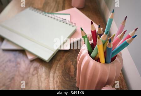 Farbstifte und Notizbücher auf einem Schreibtisch aus Holz Stockfoto
