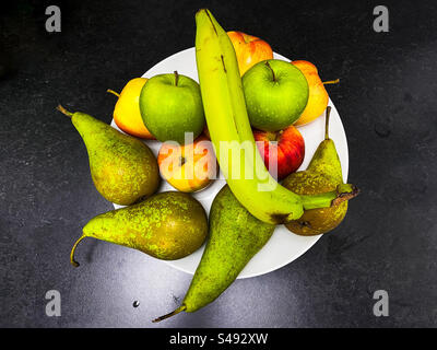 Ein Spieler mit Früchten auf einer dunklen Arbeitsfläche, von oben gesehen. Stockfoto