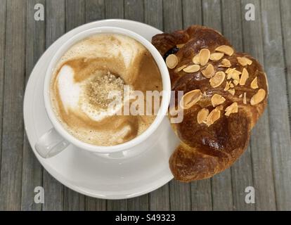 Cappuccino mit braunem Zucker und Mandelcroissant an der Bar Stockfoto