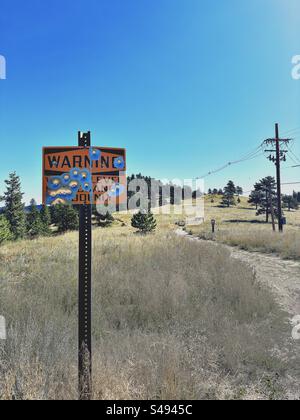 Warnschild im Eldorado Canyon State Park mit Einschusslöchern. Wanderweg in Colorado im September. Telefonstange auf die andere Seite. Stockfoto