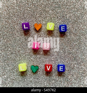 Liebe ist Liebe, die mit bunten Buchstaben auf einem glitzernden Hintergrund geschrieben wird Stockfoto