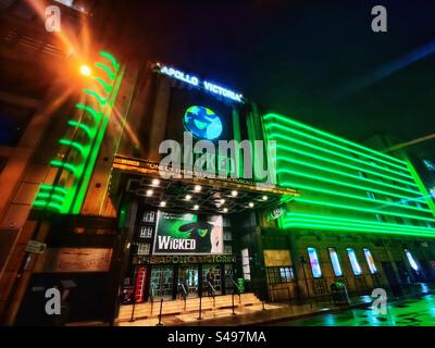 Landschaftsfoto des Apollo Theatre in Victoria, London, bei Nacht mit grüner Neonbeleuchtung, Werbung für „Wicked“, ein lang laufendes Musical, das auf dem Zauberer von Oz basiert. Nachtleben auf der Straße. Stockfoto