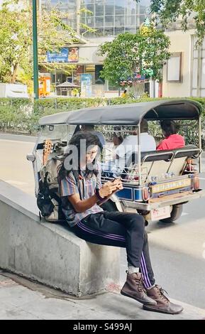 Ein Busker sitzt auf der Sukhumvit Road in Bangkok, Thailand. Stockfoto