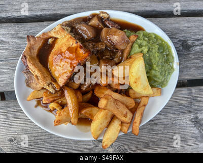 Fleisch- und Kartoffelkuchen mit Pommes Frites und matschigen Erbsen Stockfoto