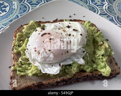 Pochiertes Ei mit roten Pfefferflocken auf Avocadotoast zum Frühstück. Stockfoto