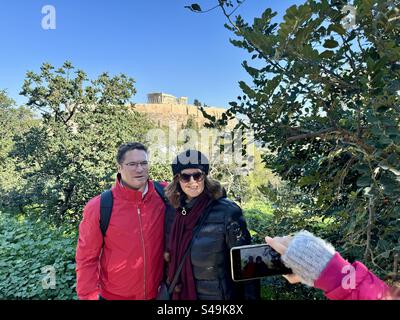 Flitterwochen-Touristenpaar, das Fotos auf dem Pnyx-Berg mit dem acrópole von Athen im Hintergrund macht. Stockfoto