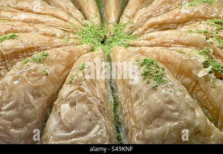 Nahaufnahme traditioneller griechischer Baklava aus Phyllo-Teig, zerstoßenen Nüssen und eingeweicht in Honigsirup, garniert mit zerstoßenen Pistazien. Stockfoto