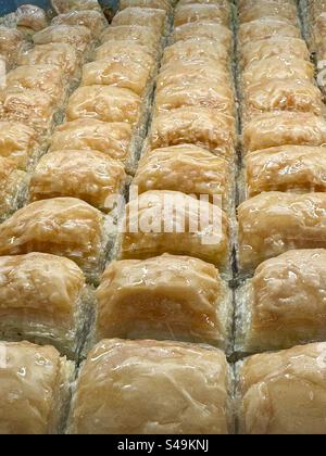 Frisch gebackenes, traditionelles griechisches Baklava-Gebäck, ordentlich in Reihen angeordnet und mit Sirup glitzernd. Traditionell aus Athen, Griechenland Stockfoto