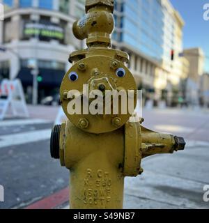 Quadratisches Bild, gelbe Zündkerze (Feuerhydrant) mit guten Augen an einer Straßenecke in Downtown Los Angeles, CA, tagsüber Stockfoto