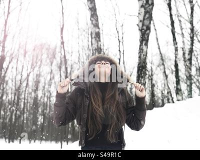 Eine junge Frau genießt Schnee im Wald Stockfoto
