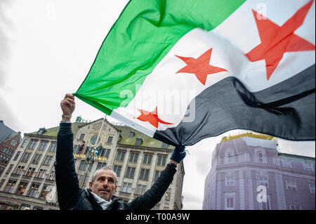 Amsterdam, Nordholland, Niederlande. 16 Mär, 2019. Eine syrische Mann hält eine syrische Flagge während der Demonstration. Der syrischen Gemeinde in den Niederlanden, der Dam Platz im Zentrum von Amsterdam nahm für Freiheit und Menschenwürde zu verlangen nach 40 Jahren repressive Diktatur. Vor acht Jahren, fing eine Revolution in Syrien. Die Proteste ein Bürgerkrieg, der Millionen Vertriebenen hat, was zu einer der größten humanitären Flüchtlingskrise in der modernen Geschichte. Credit: Ana Fernandez/SOPA Images/ZUMA Draht/Alamy leben Nachrichten Stockfoto