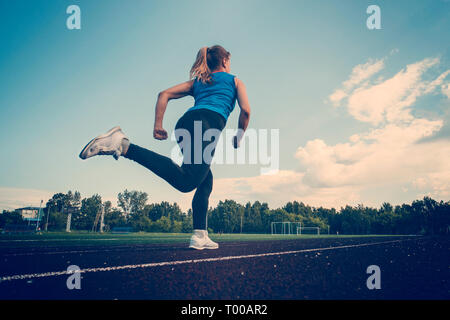 Athletische junge Sportlerin sprinten auf der Laufstrecke Stadion. Sicht nach hinten. Stockfoto