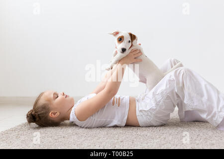 Kinder, Haustiere und Tiere Konzept - Kind Mädchen spielen mit ihrem Jack Russell Terrier Welpen im Innenbereich Stockfoto