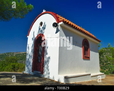 Kleine weiße Kapelle mit lebendigen Farben unter strahlend blauem Himmel. Stockfoto