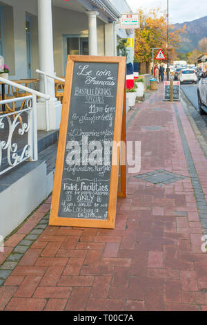 Menü Vorstand außerhalb eines Cafe Restaurant auf dem Bürgersteig Werbung Getränke und Preise am Tag der Bastille Fest Feier in Franschhoek, Cape Winelands Stockfoto