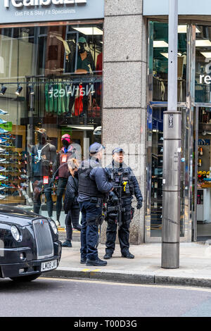 Bewaffnete Polizisten patrouillieren High Street Kensington in London. Stockfoto