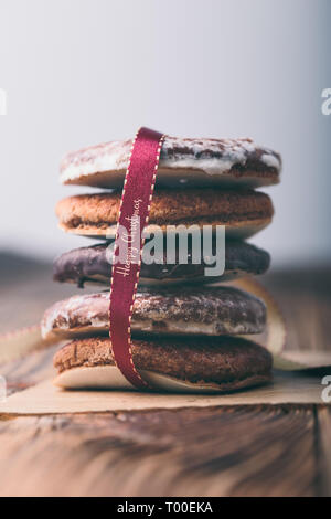Ein paar Lebkuchen Cookies in red ribbon Frohe Weihnachten verpackt. Einfachen Hintergrund. Hochformat Stockfoto