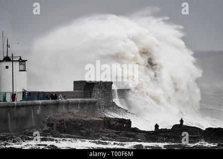 Große Wellen schlagen die Küste als Zuschauer von den Felsen bei Porthcawl, Wales anschauen. Stockfoto