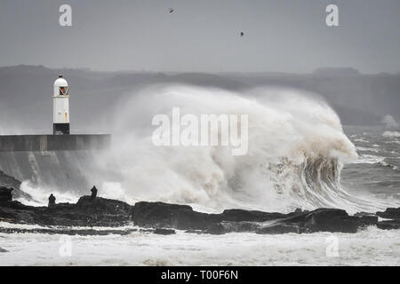 Große Wellen schlagen die Küste als Zuschauer von den Felsen bei Porthcawl, Wales anschauen. Stockfoto