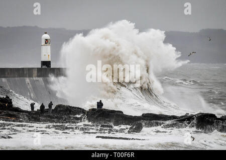 Große Wellen schlagen die Küste als Zuschauer von den Felsen bei Porthcawl, Wales anschauen. Stockfoto