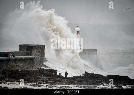 Große Wellen schlagen die Küste als Zuschauer von den Felsen bei Porthcawl, Wales anschauen. Stockfoto