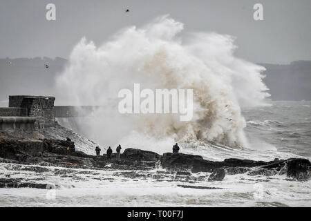 Große Wellen schlagen die Küste als Zuschauer von den Felsen aus sehen Sie in das Meer bei Porthcawl, Wales. Stockfoto