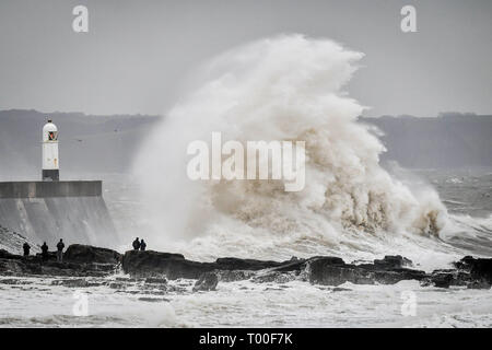 Große Wellen schlagen die Küste als Zuschauer von den Felsen aus sehen Sie in das Meer bei Porthcawl, Wales. Stockfoto