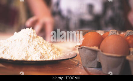 Zutaten zum Backen selbstgebackenes Brot. Eier, Mehl. Holz- Hintergrund, Seitenansicht. Soft Focus und Licht Stockfoto