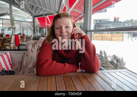 Blond kaukasische Frau ist, am Telefon zu sprechen und lächelnd. Stockfoto