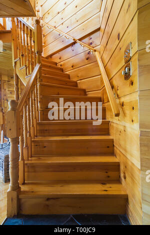 Die Kiefernholztreppe führt vom Wohnzimmer in die obere Etage, in ein Stück östliches weißes Kiefernholz- und Holzhaus. Stockfoto