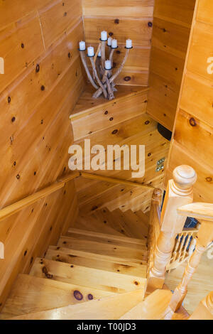 Eine Kiefernholztreppe führt von oben in die untere Etage, in ein Stück östliches weißes Kiefernholz- und Holzhaus. Stockfoto