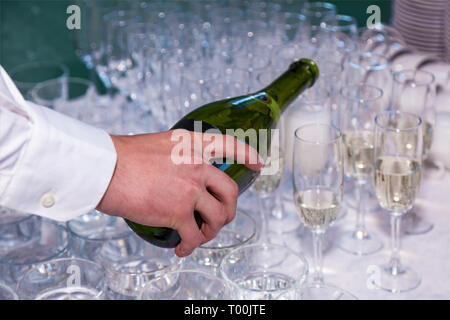 Der Kellner gießt Sekt in die Gläser aus einer Flasche in ein Restaurant. Gastronomie, Bankett Stockfoto