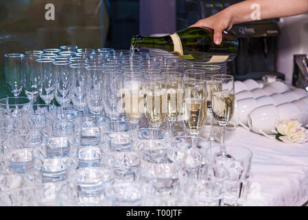 Der Kellner gießt Sekt in die Gläser aus einer Flasche in ein Restaurant. Gastronomie, Bankett Stockfoto