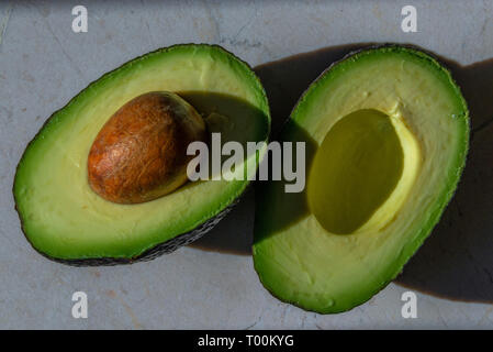 Ein perfekt reife Avocado Obst, mit Saatgut, in zwei bereit zu schaufeln. Die Avocado gehört zur Gattung Persea in der lauraceae Familie. Stockfoto