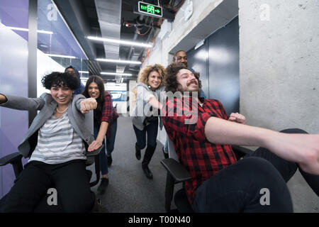 Multiethnics startup Business Team von Software-Entwicklern Spaß beim Racing auf Bürostühle, aufgeregt, diverse Mitarbeiter Lachen genießen Lustig ein Stockfoto