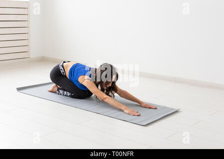 Gesunder Lebensstil, Menschen und Sport Konzept - junge Frau mit lockigem Haar Yoga auf weißem Hintergrund Stockfoto