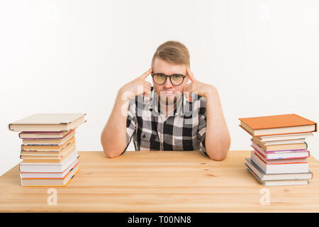 Menschen, Wissen und Bildung Konzept - Müde männliche Kursteilnehmer am Tisch sitzen mit Bergen von Büchern und will nicht bis zu Studie Stockfoto