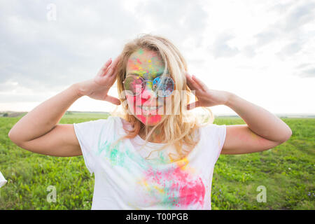 Holi Festival und Personen Konzept - glückliche Frau in Farbe auf die Natur Stockfoto