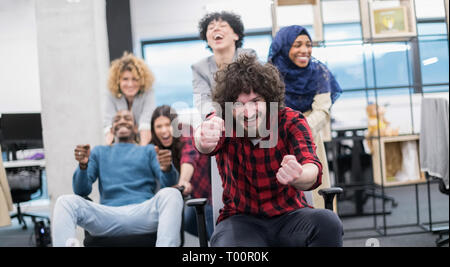 Multiethnics startup Business Team von Software-Entwicklern Spaß beim Racing auf Bürostühle, aufgeregt, diverse Mitarbeiter Lachen genießen Lustig ein Stockfoto