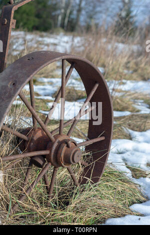 Vintage iron Rad auf trockenem Gras und Schnee closeup Stockfoto