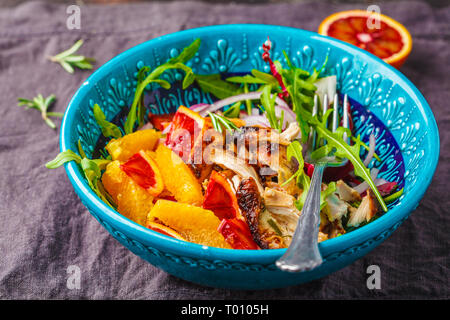 Gegrilltes Hähnchen und orange Salat mit Zwiebeln in einem blauen Platte auf weißem Hintergrund. Stockfoto