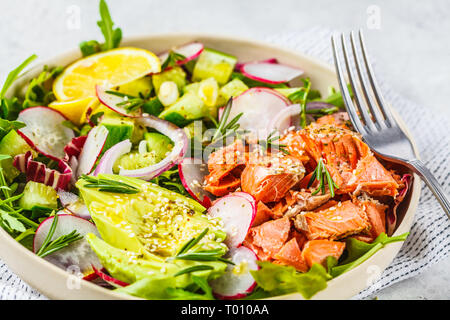 Gebackene sockeye Salat mit Avocado, Gurken, Rettich und Rucola in eine weiße Platte. Stockfoto