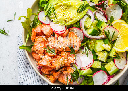 Gebackene sockeye Salat mit Avocado, Gurken, Rettich und Rucola in eine weiße Platte. Stockfoto