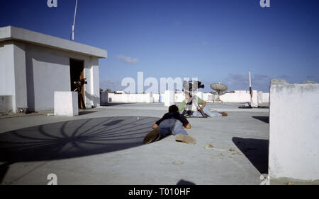 25. Oktober 1993 Mitglieder der Medien liegen niedrig auf dem Dach des Sahafi Hotel, eine Feuer-Kampf tobt an der K 4 Kreisverkehr in Mogadischu, Somalia. Stockfoto