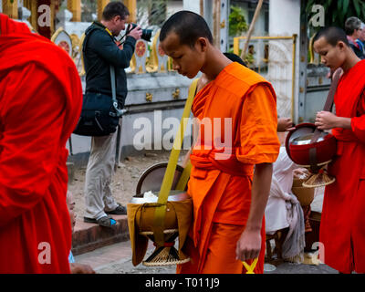 Buddhistische Mönche in orangefarbenen Gewändern Warteschlange für morgen Almosen Preisverleihung, Luang Prabang, Laos Stockfoto