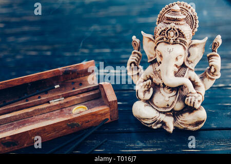 Hindu Gott Ganesh auf schwarzem Holz- Hintergrund. Statue auf Tabelle mit Sandelholz stick schließen oben mit Platz für Text kopieren Stockfoto