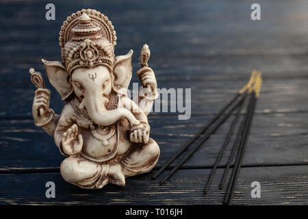 Hindu Gott Ganesh auf schwarzem Holz- Hintergrund. Statue auf Tabelle mit Sandelholz stick schließen oben mit Platz für Text kopieren Stockfoto