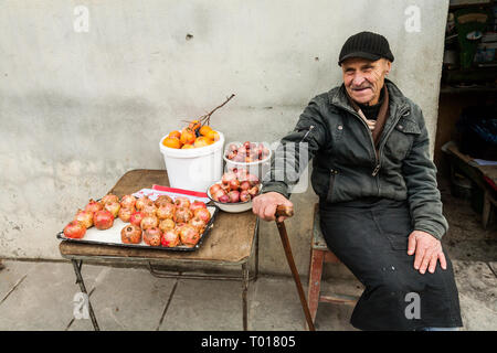 Signagi, Georgien - November 23, 2011: Der alte Mann verkauf Granatäpfel, Zwiebel und Persimmon auf einer Straße in Signagi, Georgien Stockfoto