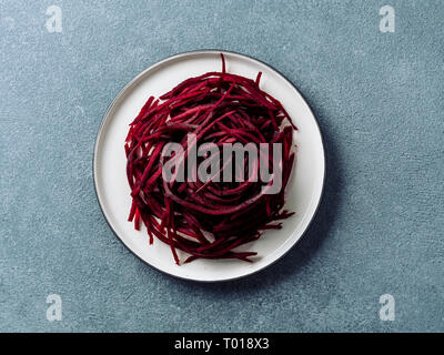 Rohe rote Beete nudeln Ansicht von oben. Gemüse Nudeln - zuckerrüben Spaghetti auf dem Teller über Stein Hintergrund. Sauber Essen, Raw vegetarisches Essen Konzept. Stockfoto