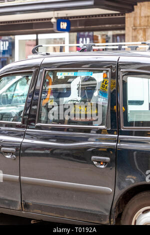 Minicab anmelden, um eine black cab Fenster reflektiert, Kensington High Street, Kensington, London Stockfoto